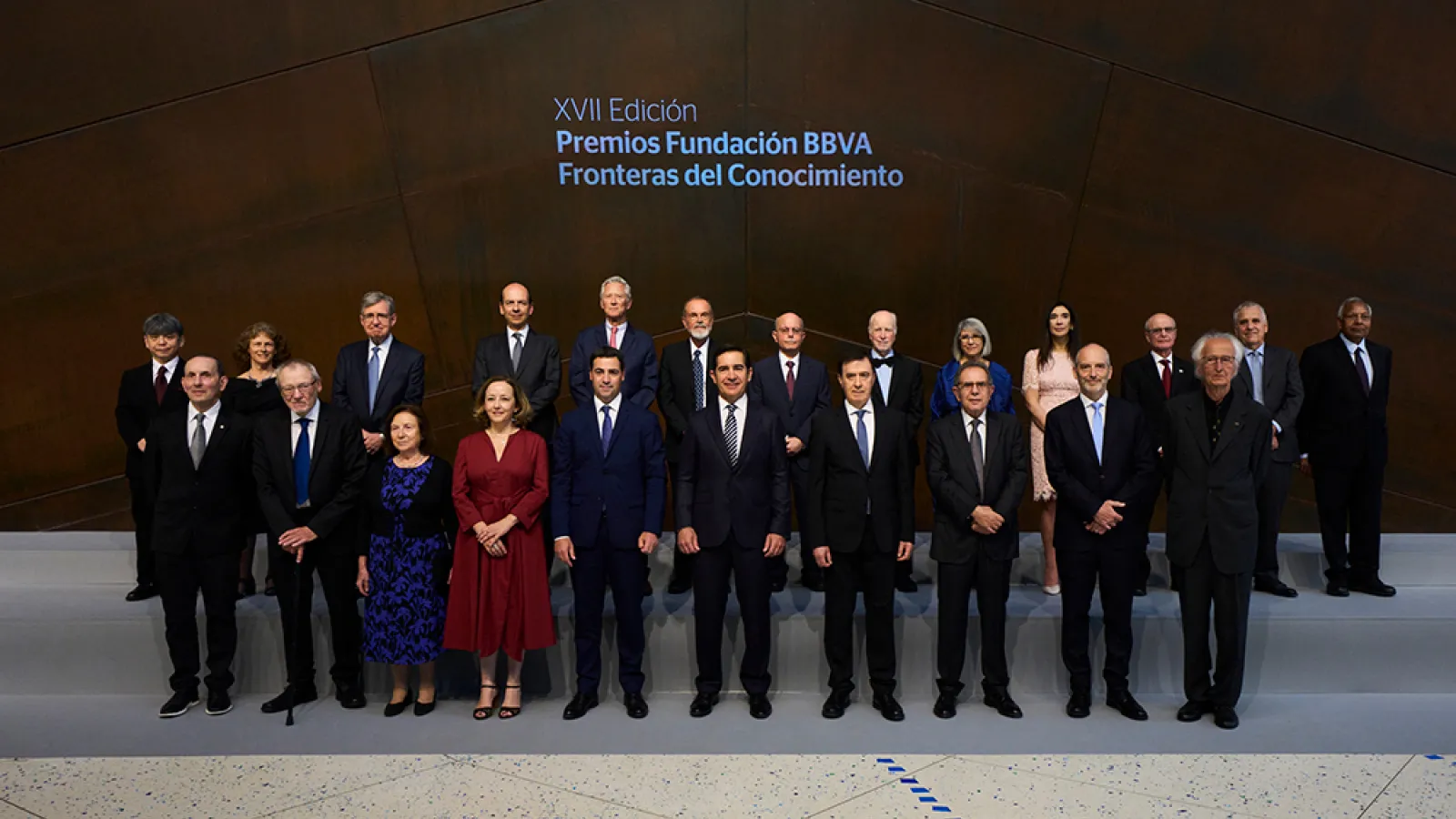 A group of 20 researchers and creatives stand for a portrait; behind them is the Spanish text "XVII Edición, Premios Fundación BBVA, Fronteras del Conocimiento"