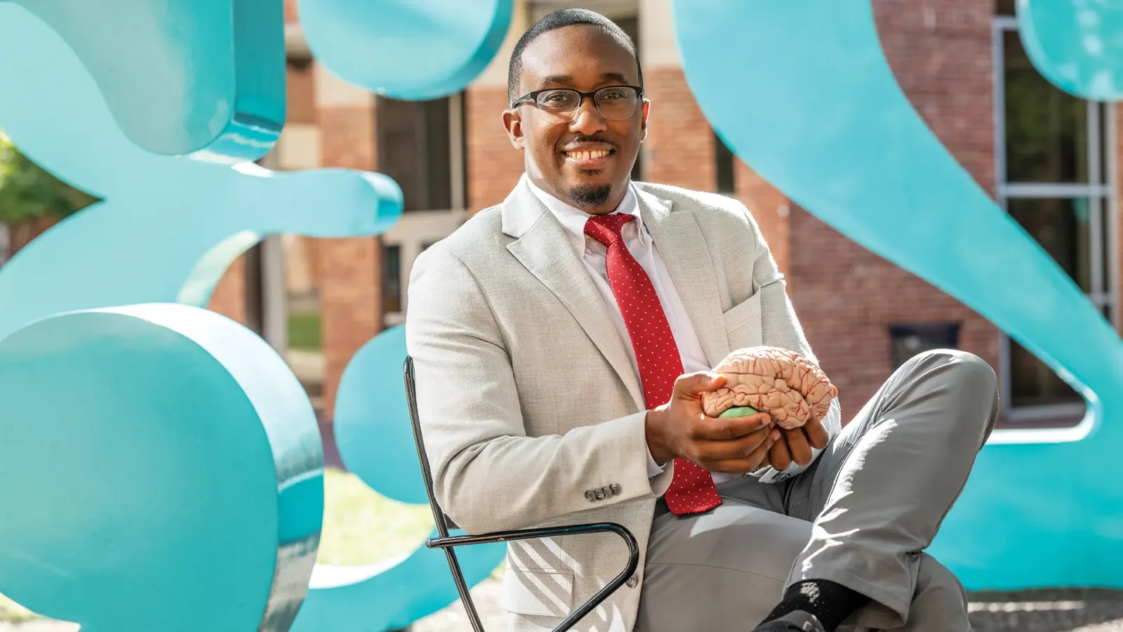 Jeremy Grant holds a model of a human brain while seated in the Garden of Constants