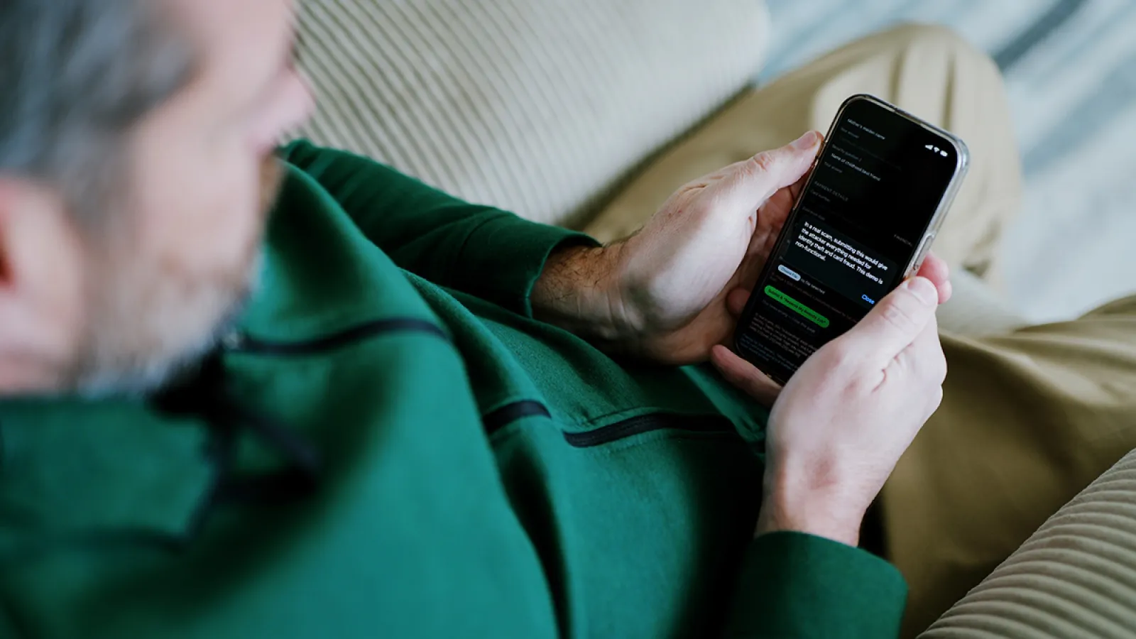 A man looking down at a smartphone that is displaying the text of an email.