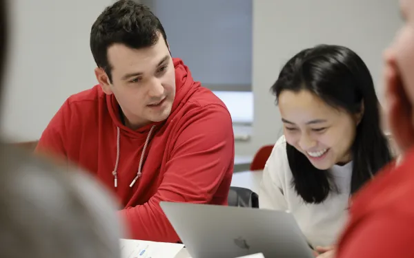 Male student and female student with laptop smiling
