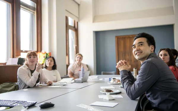 group of people gathered in business attire sitting at an indoor meeting table