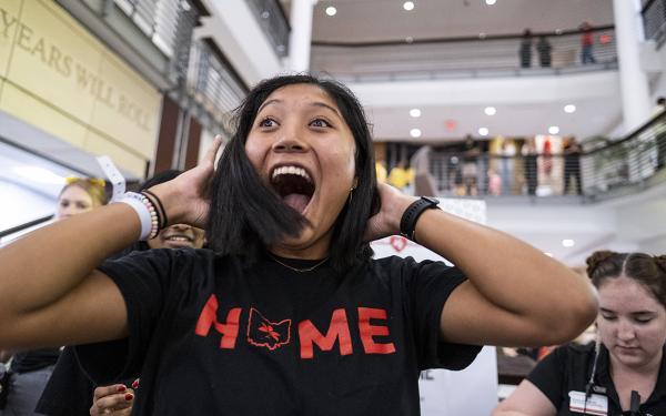 A woman wearing a "Home" shirt smiles after her hair is cut inside the Union.